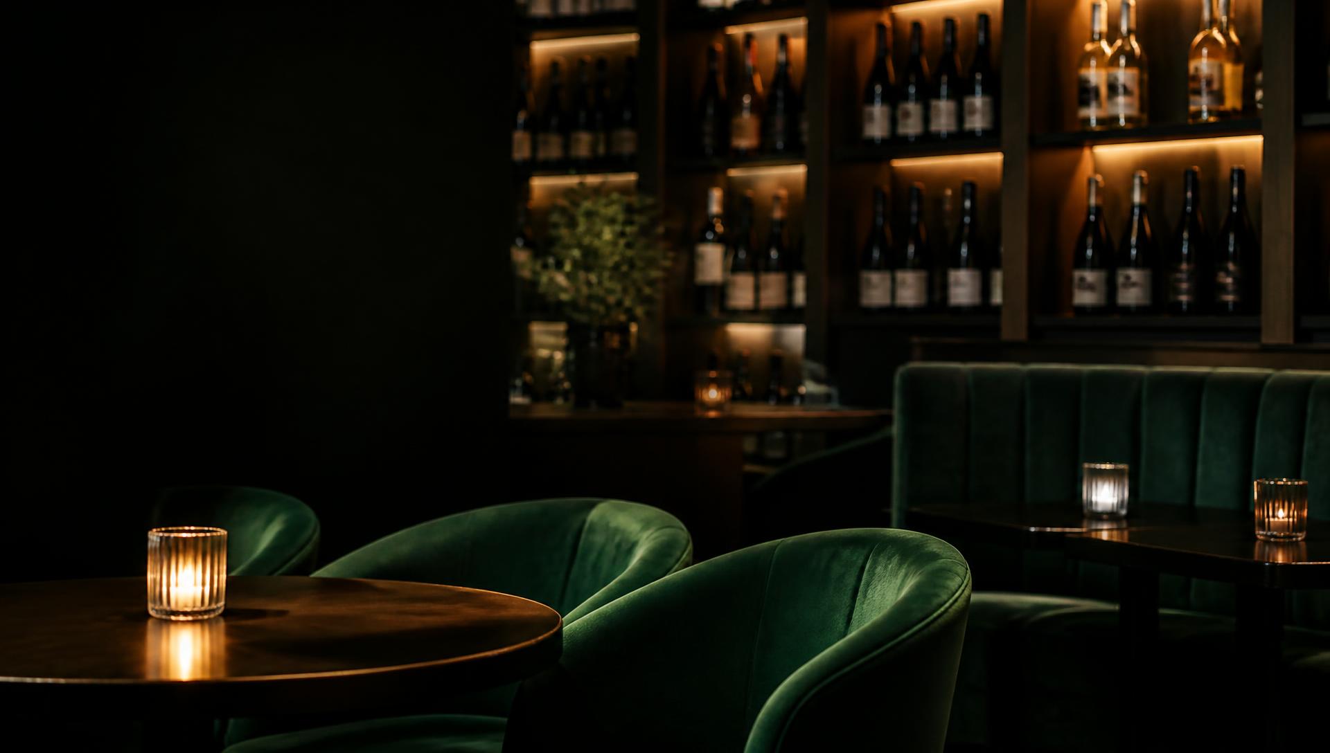 Intimate wine bar interior with emerald seating and candlelight
